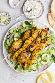 chicken kabobs with cucumber salad and pita bread on the side