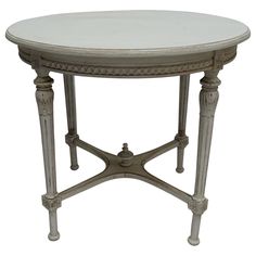 a white marble top table with ornate carvings on the legs and bottom, against a white background