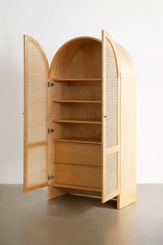 an open wooden cabinet sitting on top of a floor next to a white wall,