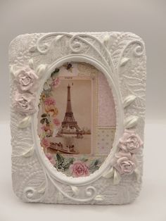 an ornate white frame with pink roses and the eiffel tower