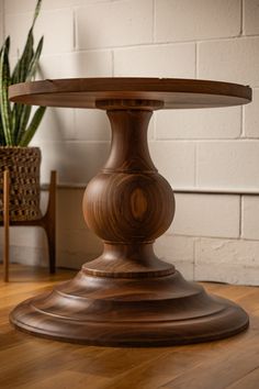 a wooden table sitting on top of a hard wood floor next to a potted plant