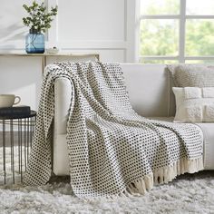 a white couch with a black and white polka dot blanket on it next to a window