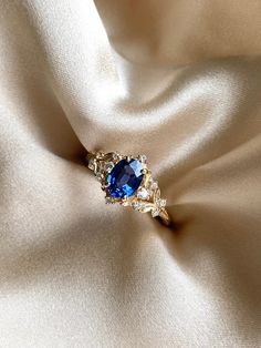 a blue ring sitting on top of a white cloth covered in gold and crystal stones