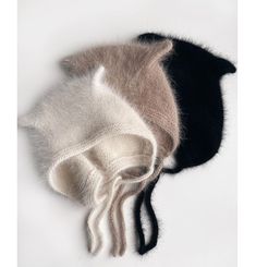 two hats are laying on top of each other, one has a cat's tail