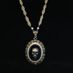 This is a large, circa 1930s, antiqued brass necklace with added brass skull. The large 2 x 1.75 inch pendant has great Victorian elements. The skull on the 1.25 x 1 inch, hematite-colored smooth glass center measures .75 inch and has been added to this vintage necklace. Even the dog tooth prongs holding the center stone in are detailed. It is surrounded by several tiny faux pearls. On the detailed, gold plated scalloped framework are four, .25 inch cut hematite-colored glass stones.  The hemati Antique Silver Victorian Metal Necklace, Victorian Antique Silver Necklace, Victorian Antique Silver Metal Necklace, Victorian Antique Silver Nickel-free Necklace, Vintage Halloween Jewelry Gift, Bronze Gothic Jewelry For Gift, Antique Silver Gothic Jewelry For Formal Occasions, Nickel-free Antique Gold Metal Jewelry, Nickel-free Metal Victorian Necklace