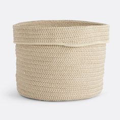 a large round basket with handles and braiding on the sides, in natural color