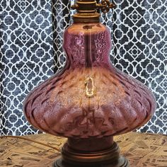 a glass vase sitting on top of a wooden table next to a blue and white wall