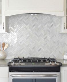 a stove top oven sitting inside of a kitchen next to white cabinets and counter tops