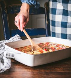 a person is spooning food out of a pan with a wooden spoon in it