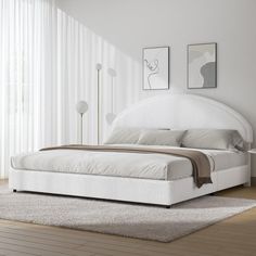 a white bed sitting in a bedroom on top of a hard wood floor next to a window