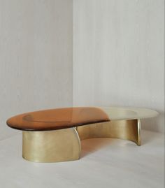 an oval table with a wooden top and metal base in front of a white wall