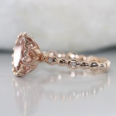 This hearty and elegant Morganite ring features large oval shaped natural Morganite. It is set into a gorgeous droplet basket setting on top of a diamond bezel pebble band. Absolutely gorgeous and yet unique gemstone to serve as your engagement or anniversary ring. *Style # R115E-11X9-Morg-14KRCenter Stone*Natural AAA Quality Morganite*Pinkish peach, Eye-clean (VS1 clarity) *11X9 mm Oval Cut *Approx. gemstone weight: 3.30 caratsDiamonds*Conflict Free Natural White Diamonds*Round Brilliant Cut *F Peach Eye, Morganite Engagement Ring Oval, Basket Setting, Morganite Engagement, Diamond Anniversary Rings, Morganite Engagement Ring, Vs Diamond, Detailed Ring, Morganite Ring