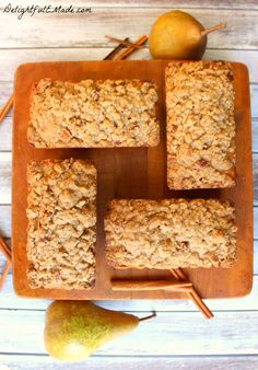 four squares of granola on a cutting board with pears and cinnamon sticks