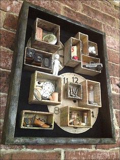 a clock mounted to the side of a brick wall next to wooden boxes filled with items