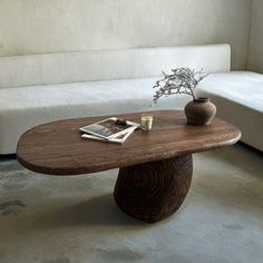 a wooden table sitting on top of a white couch next to a vase filled with flowers