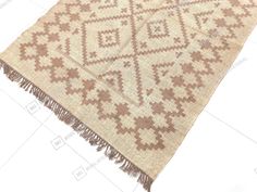 a beige and brown rug with fringes on the bottom is laying on a white surface