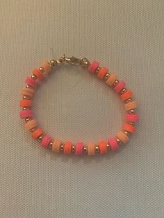 an orange and pink beaded bracelet on a white surface