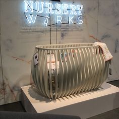 a baby crib sitting on display in front of a neon sign that says nursery works