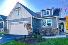 a large house with two garages and landscaping in the front yard, on a sunny day