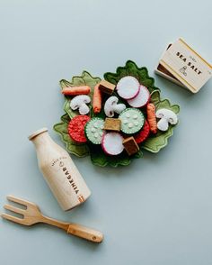 a wooden spoon and fork sitting next to a plate with sushi, rice and vegetables on it