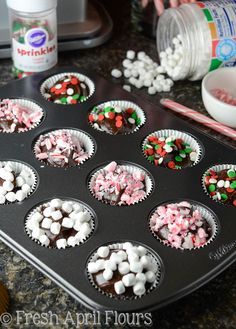 a muffin tin filled with cupcakes and marshmallows next to candy canes