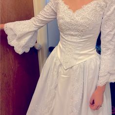 a woman in a white wedding dress is holding her hands out to the side while standing next to a door