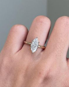 a woman's hand with a diamond ring on top of her finger, showing the center stone