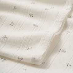 closeup of white knitted fabric with small flowers and leaves on the bottom half