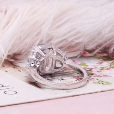 a diamond ring sitting on top of a white feather