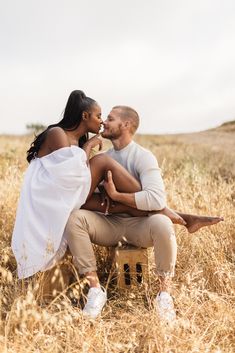 a man and woman are sitting on a bench in the middle of a wheat field