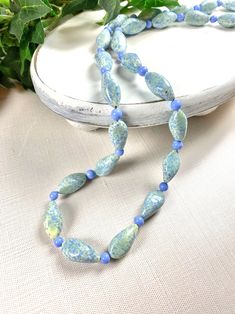 "Spectacular Murano glass necklace marries old with the new! The oblong glass beads are Vintage from the 1950's and the small periwinkle glass beads are current stock. The vintage beads have an opaque, very pale green base with periwinkle blue splashes and specks! The shape is quite unique with a sided oblong shape. The smaller periwinkle beads match the splashes to perfection! This necklace is 29.5 inches long and clasp free. It easily slips over your head but if you would prefer a lobster claw Oval Glass Gemstone Beads Jewelry, Vintage Czech Glass Oval Beaded Necklace, Oval Glass Gemstone Bead Necklaces, Glass Necklaces With Oval Gemstone Beads, Oval Gemstone Bead Necklaces, Single Strand Necklace With Czech Glass Oval Beads, Single Strand Necklace With Oval Czech Glass Beads, Handmade Oval Glass Necklace, Glass Necklace With Oval Beads For Gifts