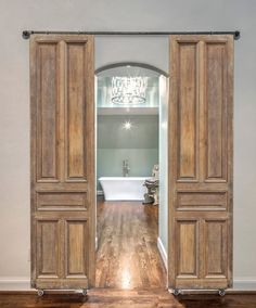 an open door leading to a bathroom with a tub and chandelier in the background