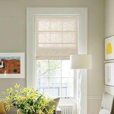 a living room filled with furniture and a window covered in shades of light brown, yellow and white