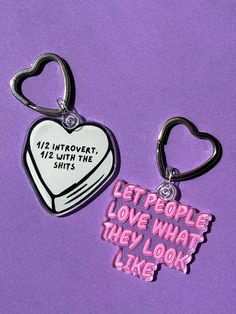 two heart shaped keychains with the words let people love what they look like