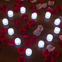 several lit candles surrounded by rose petals on a table