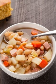 a white bowl filled with soup next to a piece of bread on top of a wooden table