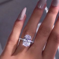 a woman's hand with a ring on top of her finger and an oval shaped diamond