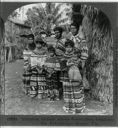 a group of people standing next to each other in front of a tree and building