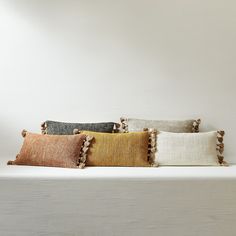 four different colored pillows sitting on top of a white shelf