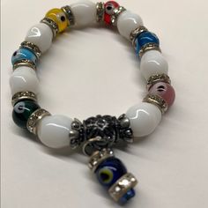 This Beautiful Brand New Multi Color Evil Eye And White Glass Beaded Stretch Glass Bracelet With Cubic Zirconia. It Is Made Of Top Quality Materials And Authentic Approx Measurements 8" Hanging Evil Eye Charm Promotes Good Luck, Healing And Defends Against Negative Energy White Stretch Bracelet With 8mm Beads, White Spiritual Bracelets With Colorful Beads, Spiritual White Bracelets With Colorful Beads, White Crystal Bracelets As Gift, White Spiritual Crystal Bracelet With Colorful Beads, White Crystal Bracelet As A Gift, White Crystal Bracelet As Gift, White Crystal Bracelet For Gifts, Spiritual White Crystal Bracelet With Colorful Beads