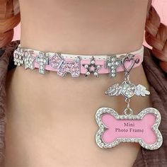 a pink dog bone charm with angel wings on it's collar is shown in front of a mannequin