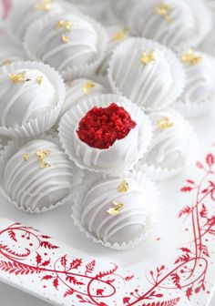 white chocolates with gold sprinkles are on a red and white plate