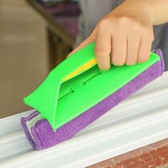 a person with a sponge on top of a window sill