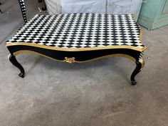 a black and white checkered coffee table with gold trimmings on the legs