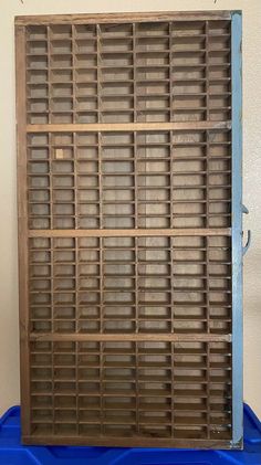 a blue plastic container with wooden slats on the top and bottom, in front of a white wall