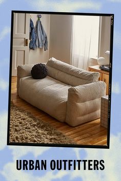 a couch sitting on top of a wooden floor in front of a blue and white wall