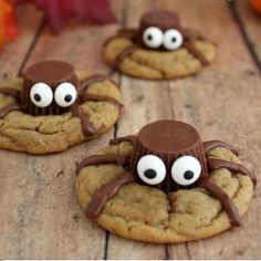 three cookies with googly eyes and chocolate on them sitting on a wooden table next to pumpkins