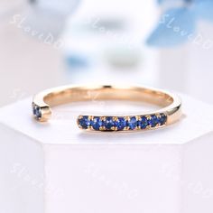 a yellow gold ring with blue sapphire stones on the inside, sitting on top of a white box