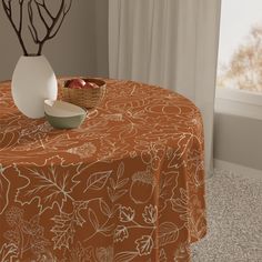 an orange table cloth with white flowers on it and a bowl of fruit sitting on top