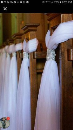 there are many white dresses hanging on the rack in front of each other with ribbons attached to them